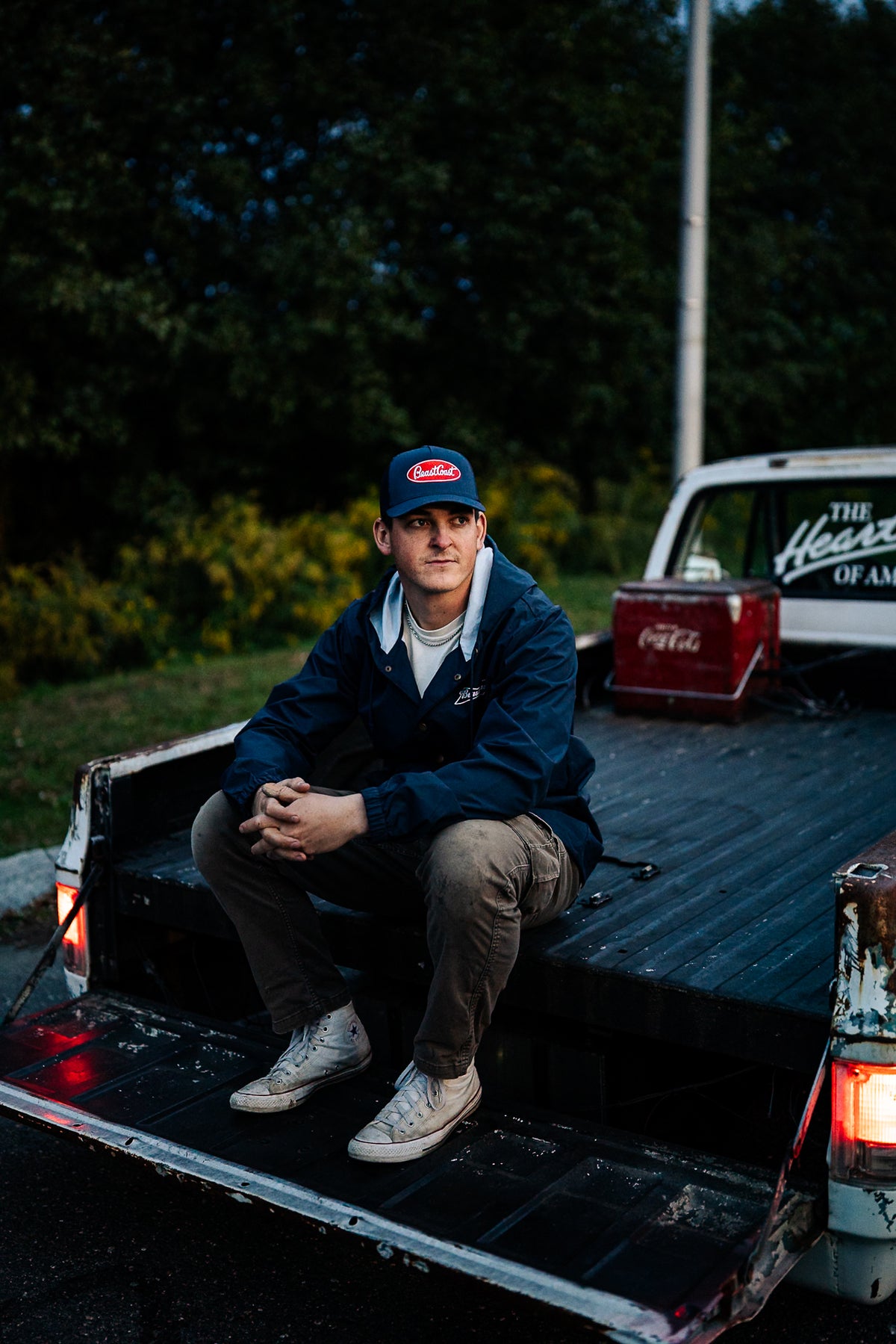 BeastCoast Americana Breaker jacket in navy, worn seated on a pickup tailgate